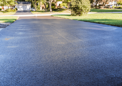 Freshly paved by Jones Asphalt VA, this black asphalt driveway shines in a suburban neighborhood on a sunny day—showcasing expert asphalt services you can trust.