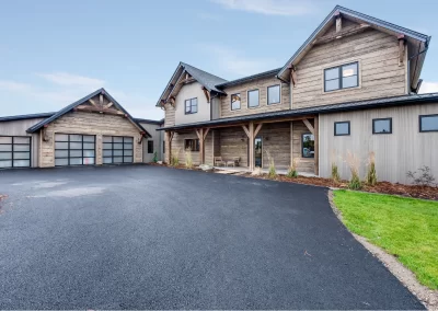 Modern rustic house with wood siding, large windows, and attached garage on a paved driveway crafted by Jones Asphalt VA Expert Asphalt Services.