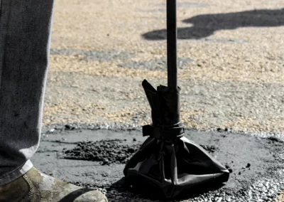 A worker's boot next to a shovel stands in a patch of fresh asphalt on a road, showcasing the precision of Jones Asphalt VA Expert Asphalt Services.