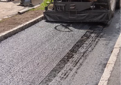 A Jones Asphalt VA machine is laying fresh asphalt on a road during a paving operation, showcasing expert asphalt services in action.