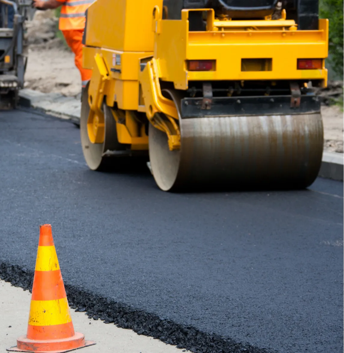 overlays-2 A road roller flattens fresh asphalt with an orange traffic cone in the foreground.