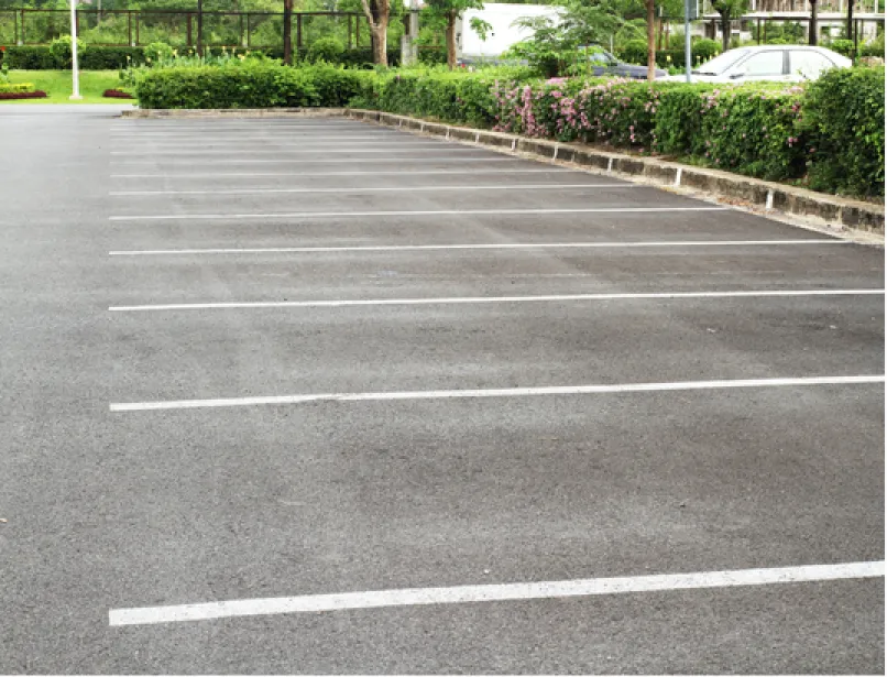 parking-2 Freshly paved black asphalt driveway in a suburban neighborhood with green lawns and trees.