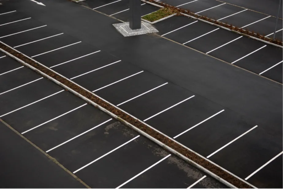 Empty parking lot with marked parking spaces and no cars, viewed from above.